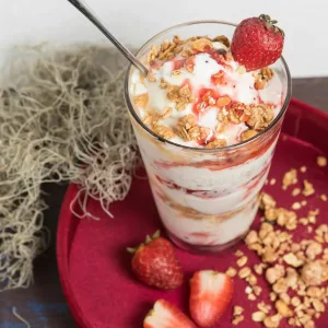 A stawberry yogurt with some strawberries.
