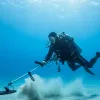 A man is detecting treasure underwater.