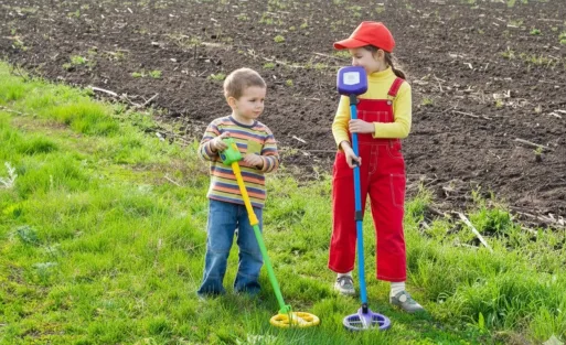 2 kids are detecting treasure on the ground.