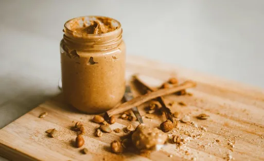 A cup of mixed nut butter with 2 spoons.